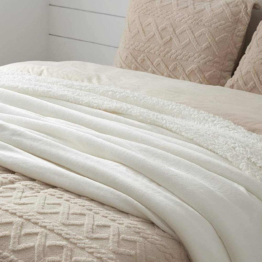 A thick sherpa fleece blanket folded on a bed